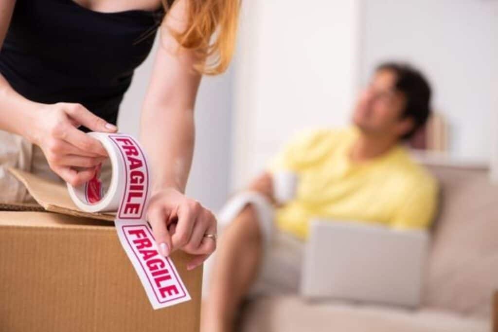 A woman placing a fragile sticker on a box