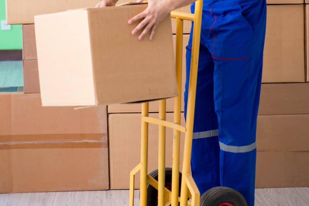 A cropped photo of a mover with trolley and is surrounded by carton in the concept of a man and van in Croydon.