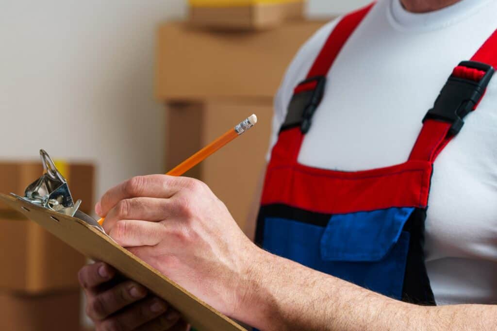 Cropped image of a professional mover in uniform making notes on a clipboard