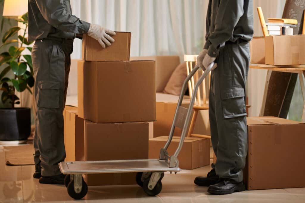 Movers put boxes to the cart into load onto the truck