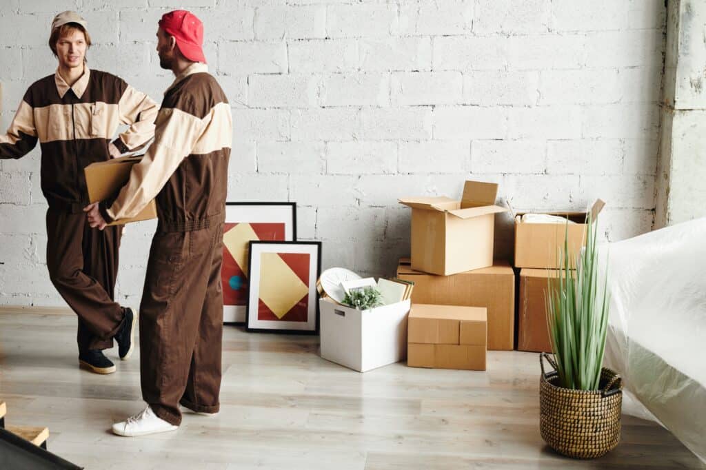 Two young movers in uniform start the packing and loading of boxes in the concept of 'What Are Home Removals Services'.